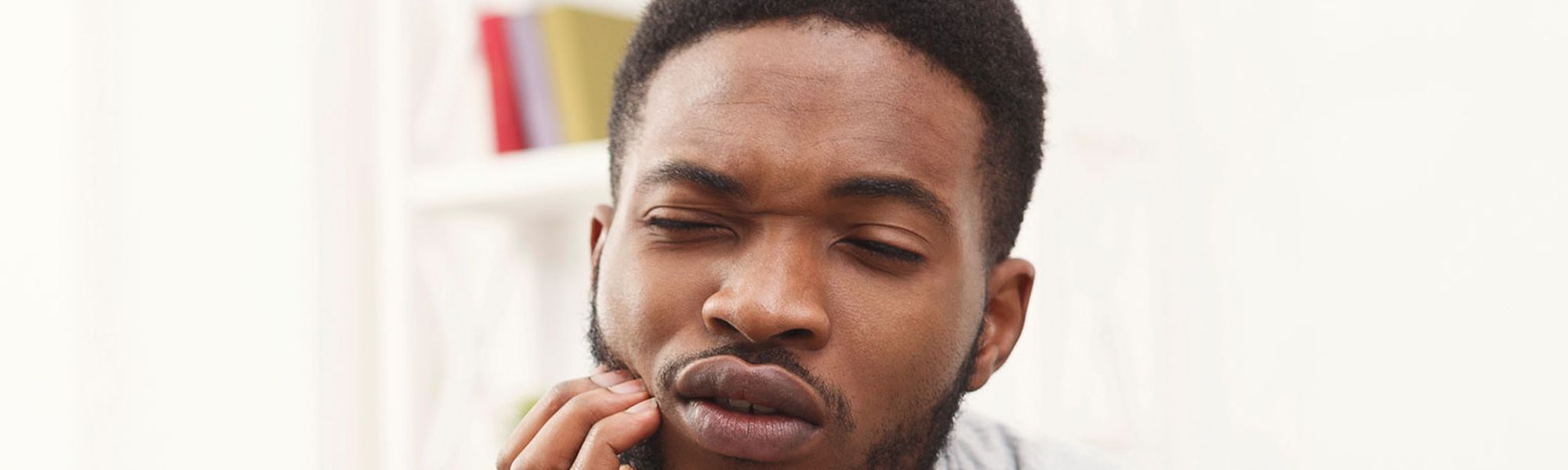 Man holding his jaw in pain from a dental emergency