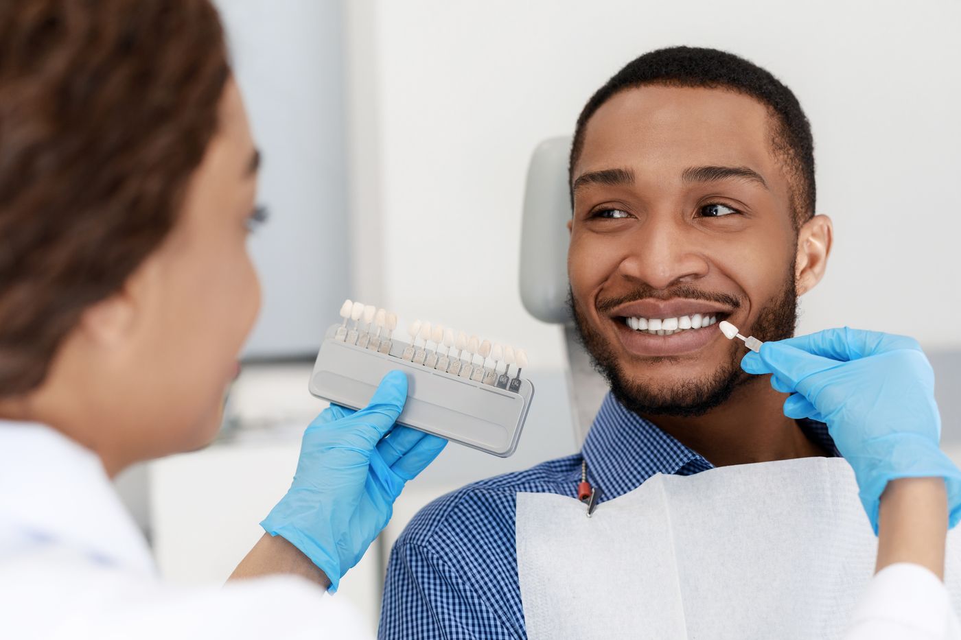 Dental hygienist demonstrating tooth shade guide to smiling patient