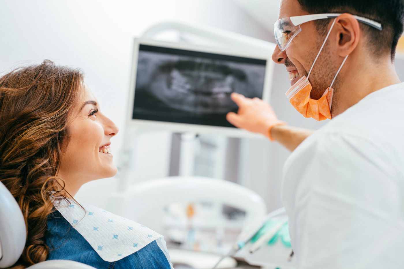 Dentist explaining X-ray to smiling patient in dental office