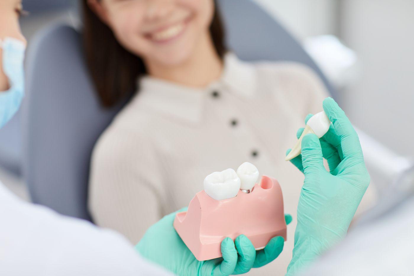 Dental professional holding pink denture model with patient smiling in dental chair
