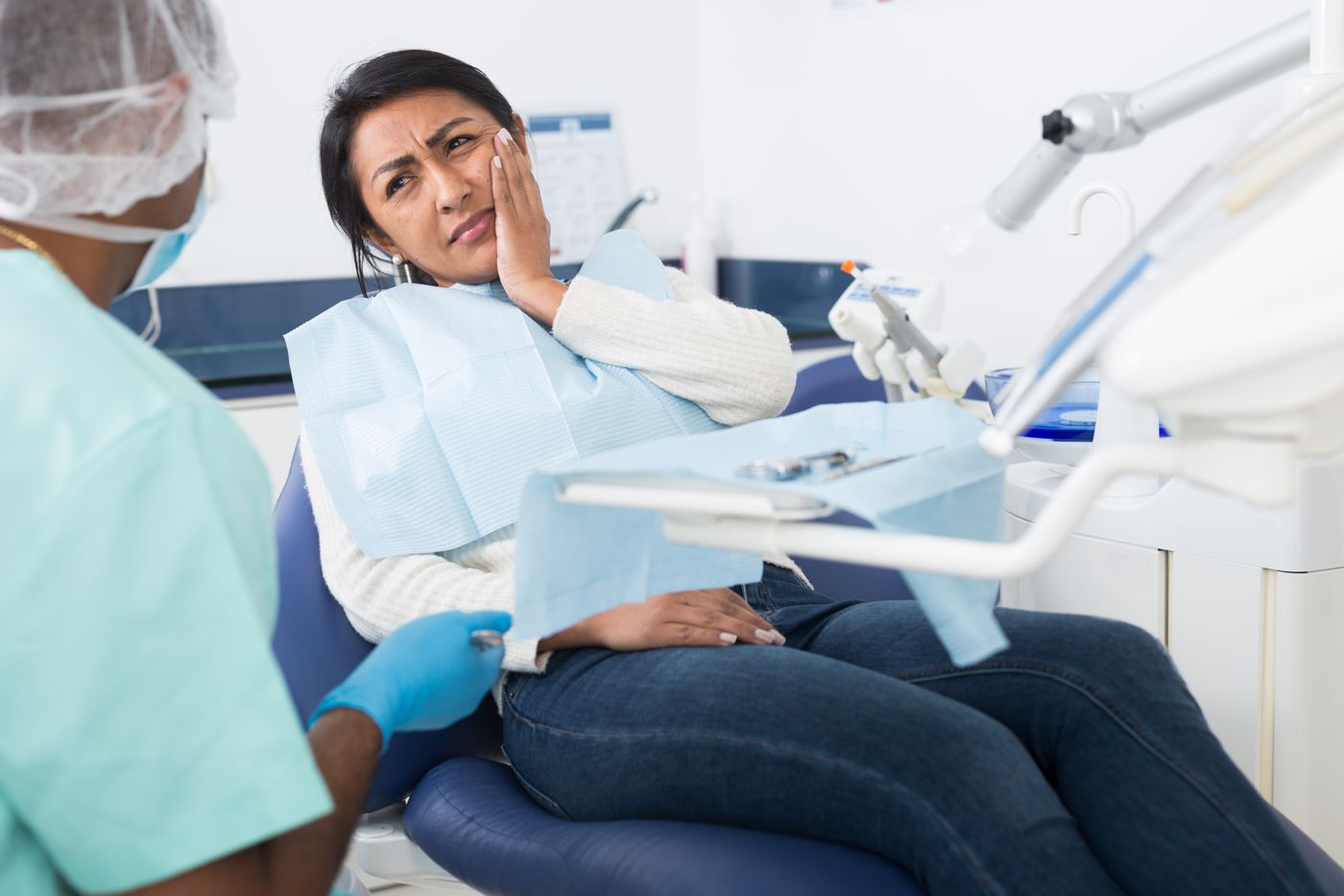 Dental assistant examining patient with jaw pain in office